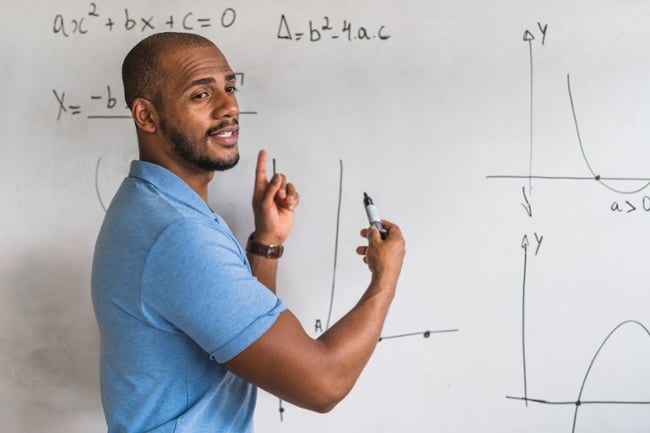 Black Male Math teacher at a whiteboard