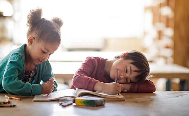 two children work on coloring book in a special education classroom